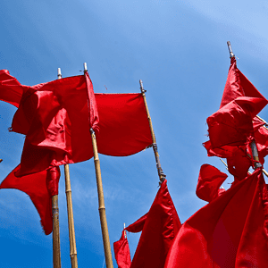 Vibrant red flags waving against a bright blue sky, symbolizing determination, motivation, and running goals.