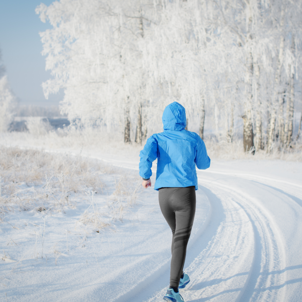 Person jogging on snowy trail in winter gear.