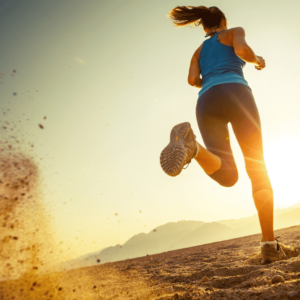 Woman running on sandy trail at sunrise.