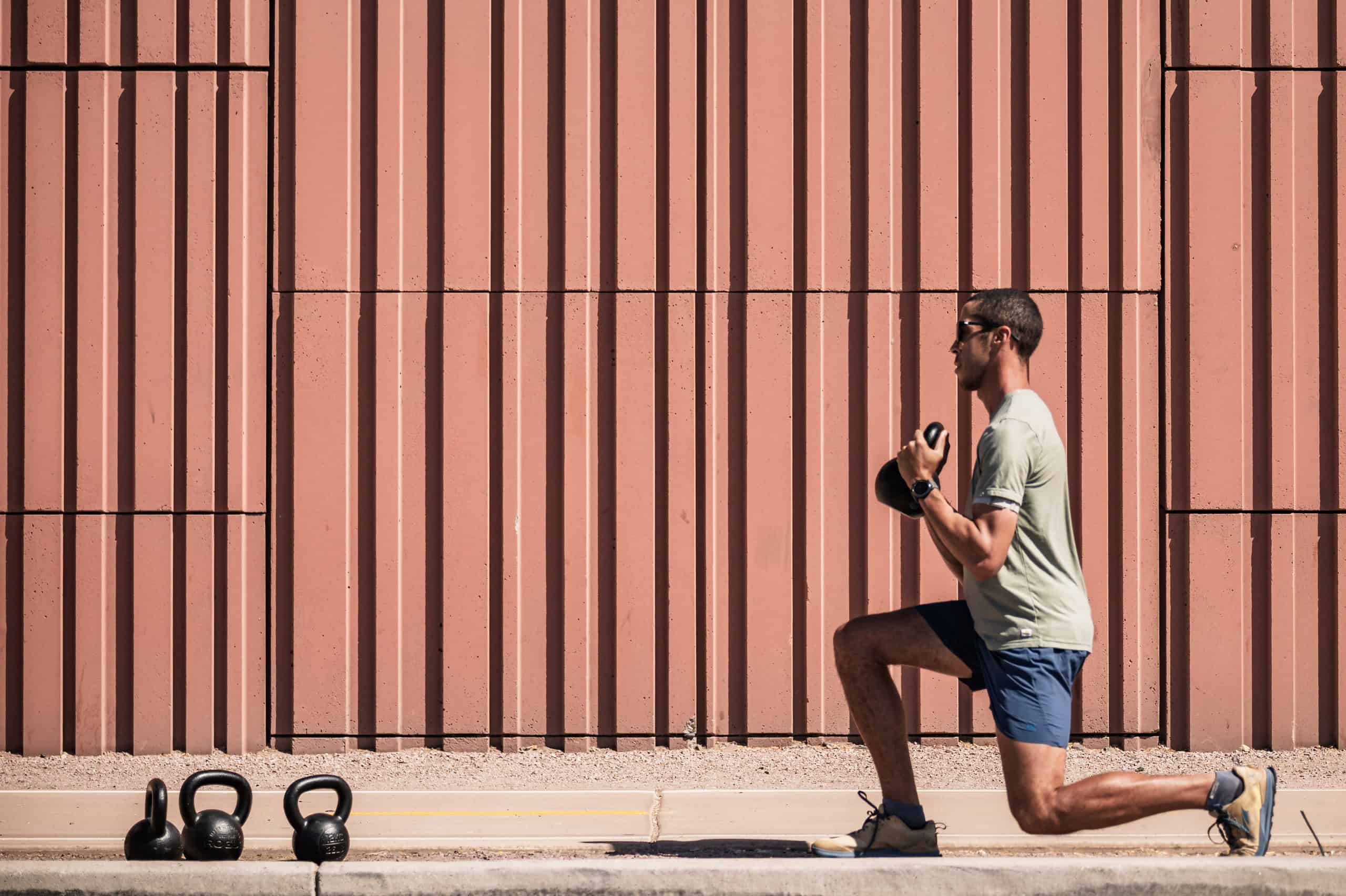 Male runner performing lunges for strength training outside.
